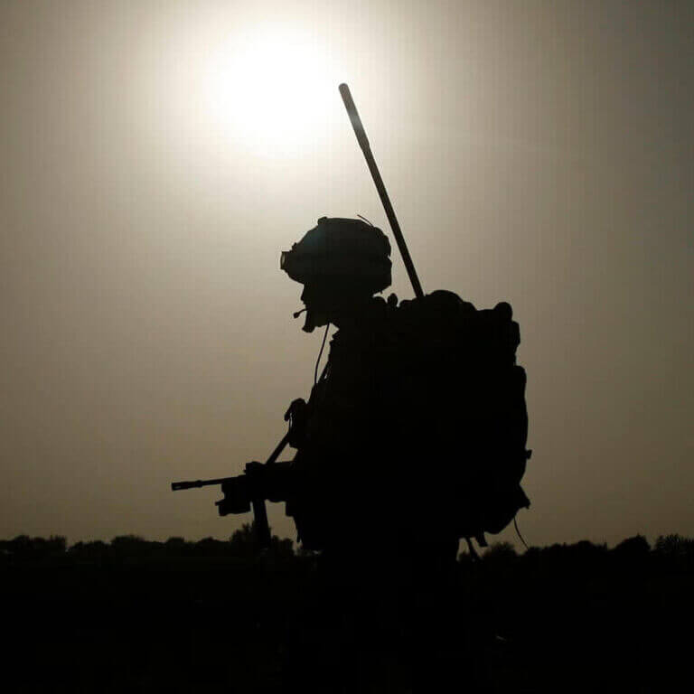 Silhouette of a soldier against a bright sun, representing the disciplined military background of South East Enforcement's field agents.