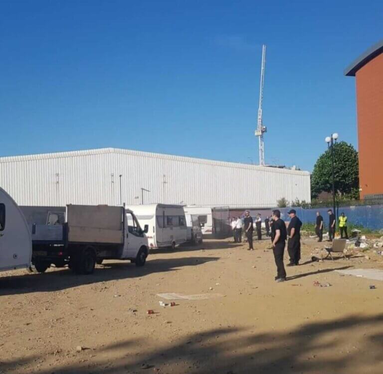 Security team overseeing the removal of caravans and vehicles from a construction site or vacant land.